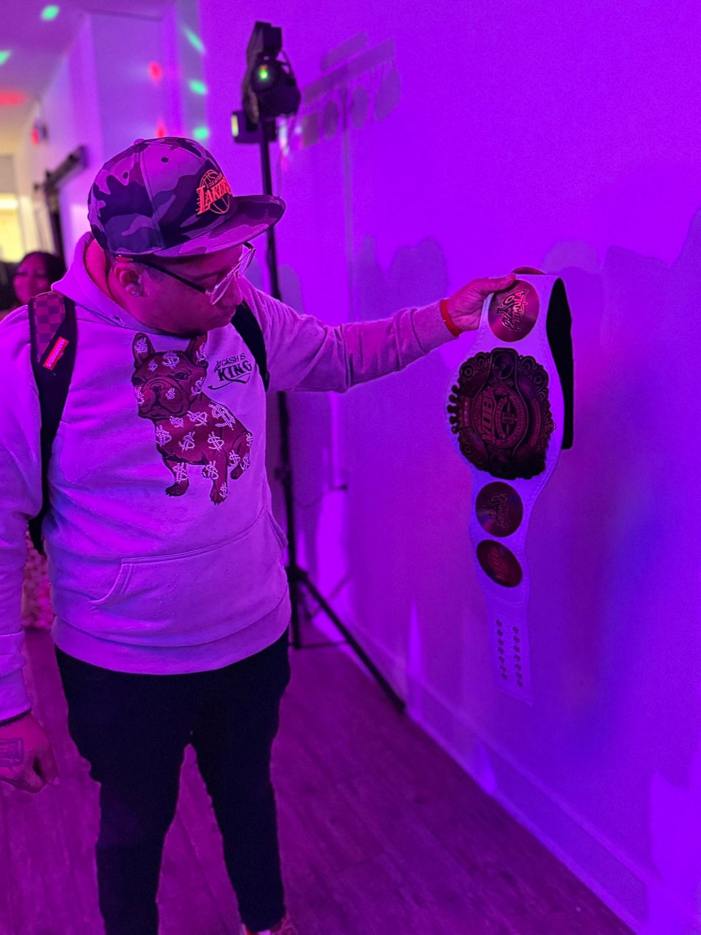 DJ Endy holding Xtreme Bar Bingo champion belt under purple lights
