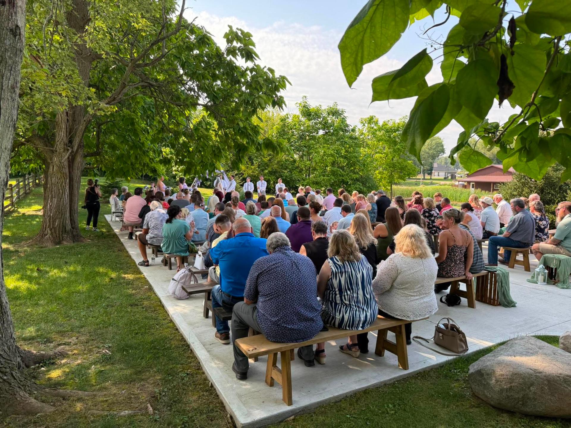 Outdoor wedding ceremony audience under summer trees